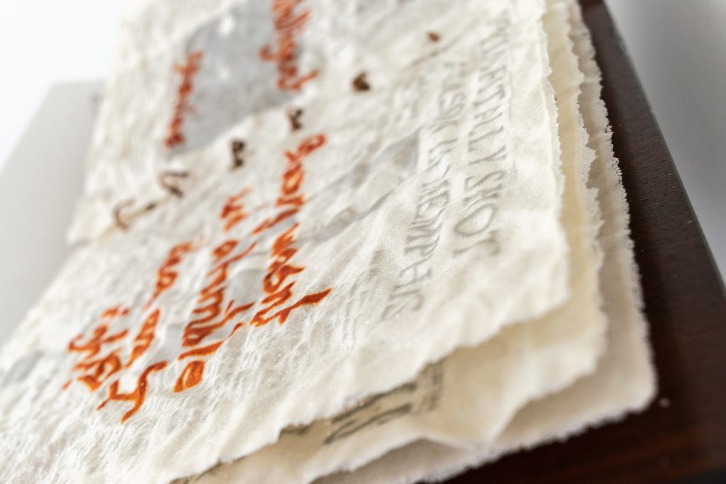 Art piece "Insert Sarcastic Title Here" in 2018 by Alise Stopina. White glass powder with printed text and hand written red satarical quotes. Zoomed in detail shot of overall piece in side angle.
