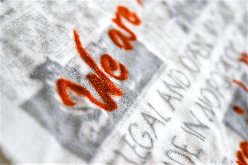 Art piece "Insert Sarcastic Title Here" in 2018 by Alise Stopina. White glass powder with printed text and hand written red satarical quotes. Zoomed in detail shot of red satarical text.
