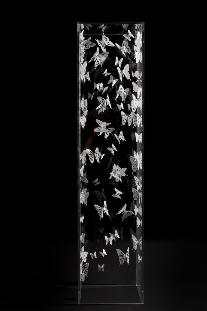 white powder glass butterflies in a glass vase on a black background by glass artist Alise Stopina